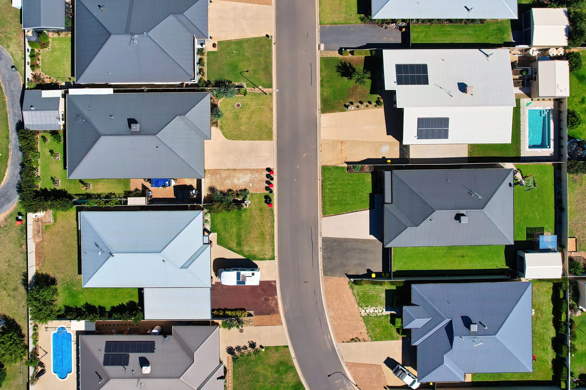 Aerial view of a new Australian housing estate with Colorbond roofs, solar panels and backyard pools.