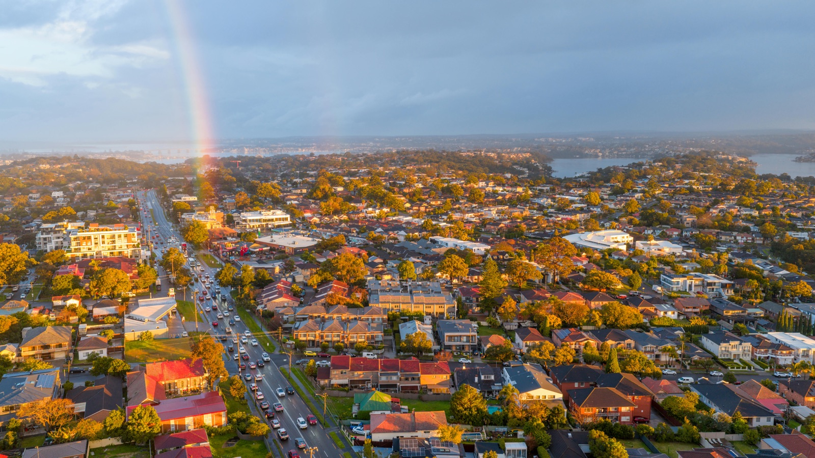 Aerial view of an Australian suburb at sunset with a rainbow over the rooftops